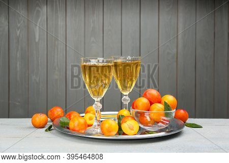 Delicious Plum Liquor And Ripe Fruits On Table Against Grey Background. Homemade Strong Alcoholic Be