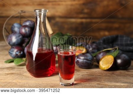 Delicious Plum Liquor And Ripe Fruits On Wooden Table. Homemade Strong Alcoholic Beverage
