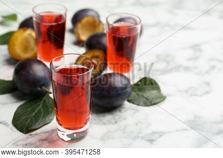 Delicious Plum Liquor And Ripe Fruits On White Table. Homemade Strong Alcoholic Beverage