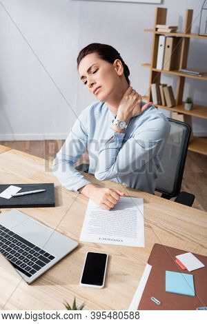 Businesswoman With Hurting Neck Sitting On Office Chair At Workplace, Stock Image
