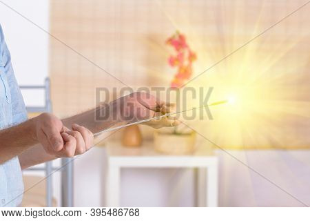 Man dowsing wirh dividing rod to locate ground water under surface or currents of earth radiation to check home for safe zones.