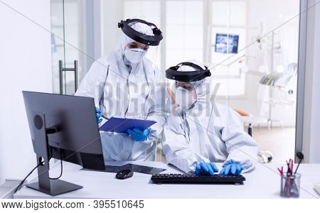 Dentist And Nurse During Global Outbreak In Protective Suit Against Infection With Covid-19. Medicin