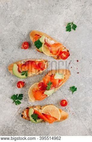 Smoked Salmon Sandwich With Cream Cheese, Lemon, Avoado And Tomato On Gray Background.