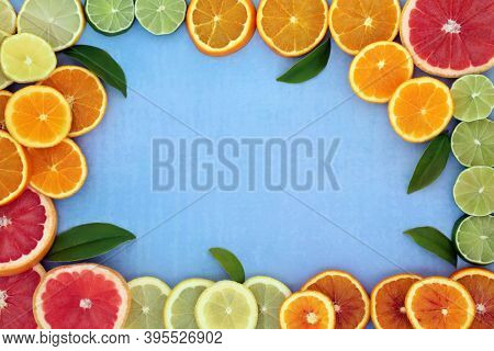 Healthy high fibre citrus fruit border for immune boost with oranges, lemons, limes & grapefruit, high in antioxidants, anthocyanins, lycopene & vitamin c. Natural health care concept on mottled blue.