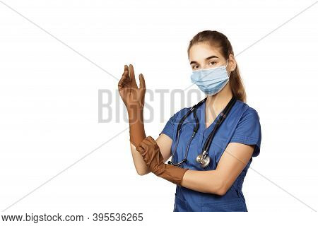 Young Female Doctor In Blue Coat Getting Ready For Work Putting On Protective Brown Surgical Gloves