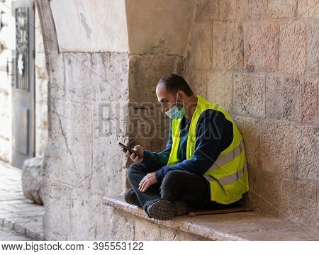 Jerusalem, Israel, November 14, 2020 : A Municipal Worker In A Reflective Vest Sits, Rests And Looks