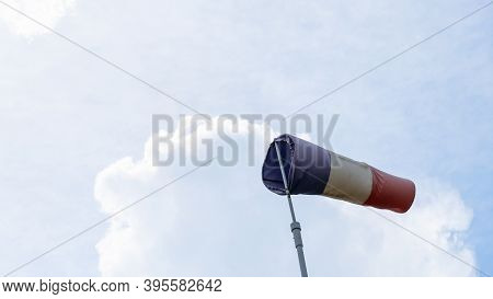 Flying Windsock Wind Vane With Red, White And Blue Lines On Dramatic Sky Background. Test Wind Direc