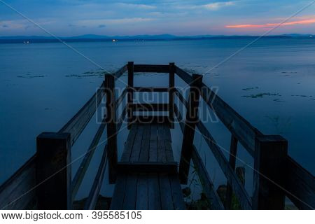 Landscape. Smooth Surface Of The Lake At Sunrise With The Horizon Line And A Wooden Pier In The Fore