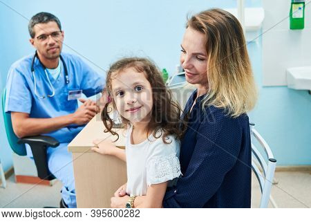 At the doctor. Smiling mother with child - little girl in clinic
