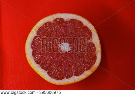 Halves Of Ripe Juicy Grapefruit, Divided In Half, Placed On A Red Fabric Background. Delicious And H