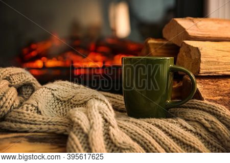 Green Cup With Hot Drink And Blanket On Table Against Fireplace