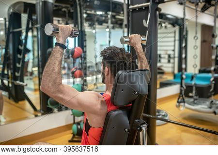 Dark-haired Man Working On His Arms On A Gym Machine