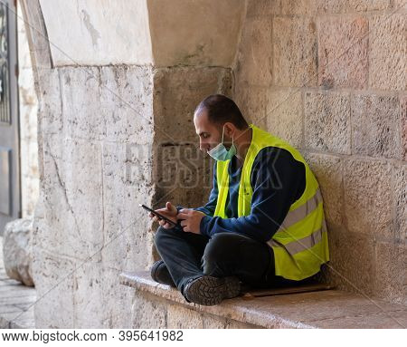 Jerusalem, Israel, November 14, 2020 : A Municipal Worker In A Reflective Vest Sits, Rests And Looks