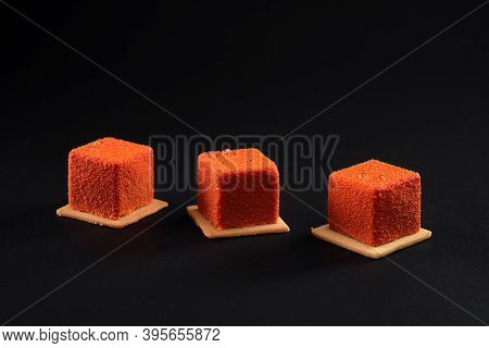 Three Small Orange Square Matte Cakes In Row On Cookies In Restaurant. Concept Of Confectionary. Clo