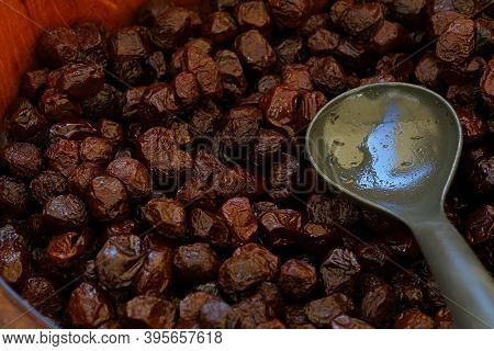Close Up Traditional Artisanal Pickled Sun Cured Black Olives And Scoop In A Rustic Natural Wooden B