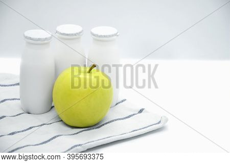 Natural liquid yogurt with probiotics in small plastic bottles and yellow apple on on kitchen towel