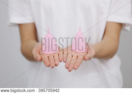 Close Up Of Woman Holding Pink Menstrual Cups Of Different Size In Her Hands On White Background. Gy
