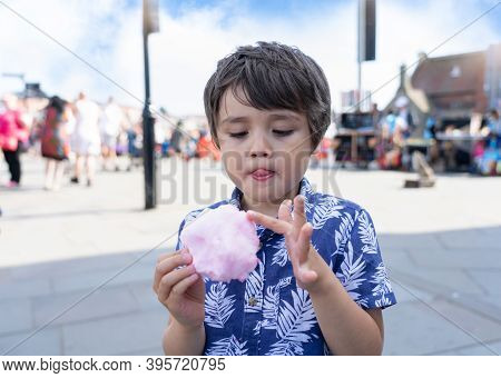 Portrait Cheerful Kid Eating Cotton Candy With Blurry People Walking On Street Background,young Boy 
