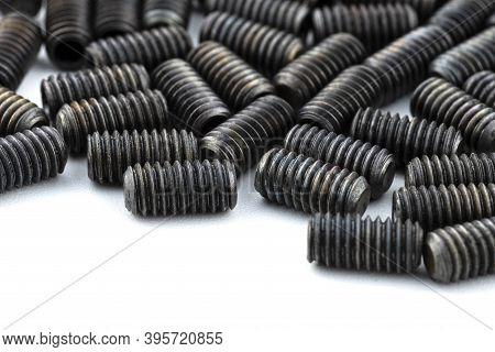 Background Made From A Macro Shot Of Scattered, Black Grub Screw On White Table.