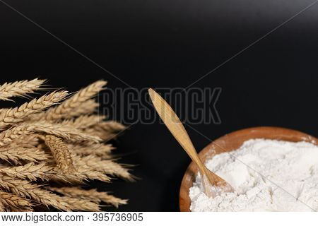 Cup With White Flour. Wooden Spoon. A Bunch Of Wheat Spikelets. The Topside Of The Screen Is Free.