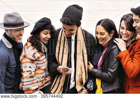 Group Of Young Adults Convene Over A Smart Phone - Winter Wear - Seasonal - Fun
