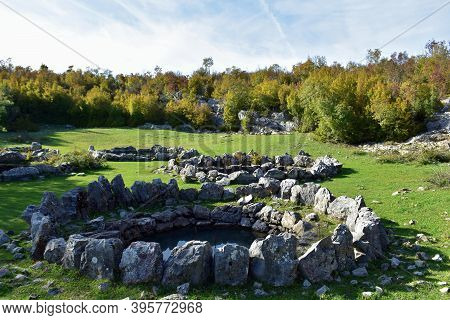 Round Stone Formations Hidden In The Forest Overgrown With Beautiful Green Grass. Pasture For Local 