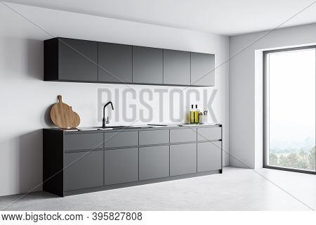 Corner Of Modern Kitchen With White Walls, Concrete Floor And Gray Cupboards With Built In Sink And 