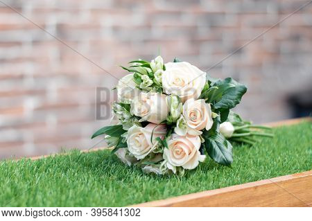 Bridal Bouquet Of White Roses On A Green Lawn Against The Background Of A Kerp Wall. Wedding Decor, 