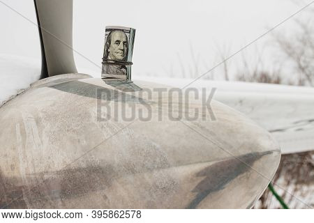 A Dollar, A Bundle Of Rolled-up Dollars Is On The Prop Of A Private Plane.