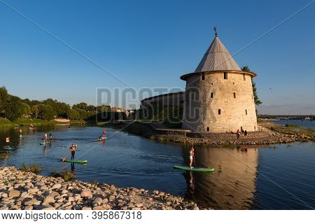 Pskov, Russia: August 21, 2020:  Sup Surfers On Pskova River. Towers And Wall Of Pskov Kremlin At Ba