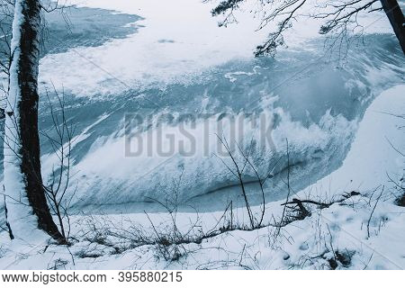 Cracks On The Surface Of The Blue Ice. Frozen Lake In Winter Mountains. It Is Snowing. The Hills Of 
