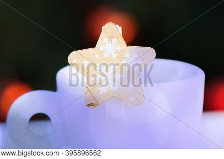 Wooden Decorative Star With Snowflakes Closeup With Violet Bokeh On White Porcelain Coffee Cup. Blur