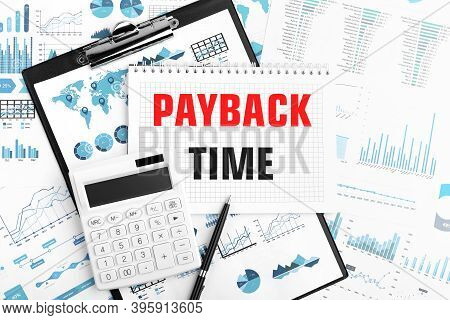Text Payback Time On Notebook. Calculator, Pen, Clipboard, Charts, Documents And Graphs On Backgroun