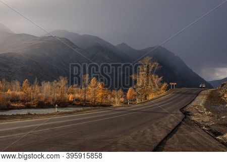 Amazing Autumn Landscape With An Asphalt Road Through The Steppe, Mountains Covered With A Golden Fo