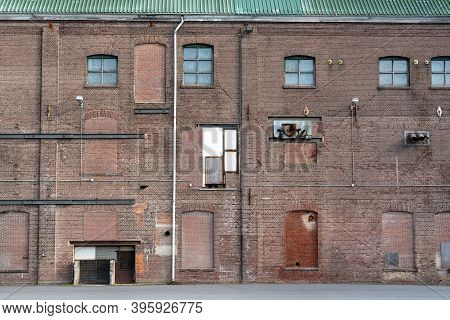 A Fragment Of An Old And Weathered Facade Of An Old Factory, Made Of Masonry, Steel And Wooden Frame
