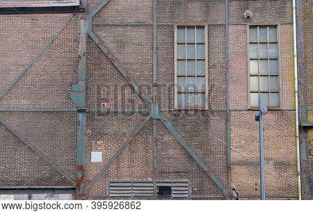 A Fragment Of An Old And Weathered Facade Of An Old Factory, Made Of Masonry, Steel And Wooden Frame