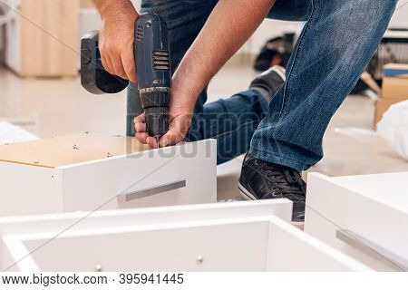 Assembly Of Furniture, The Carpenter Screws A Self-tapping Screw Into A Drawer With A Screwdriver.
