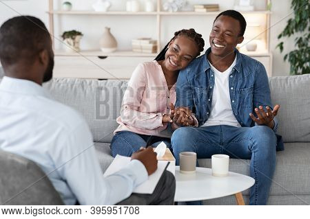 Family Counseling. Young Happy Black Couple Sitting On Couch At Psychotherapists Office, Holding Han