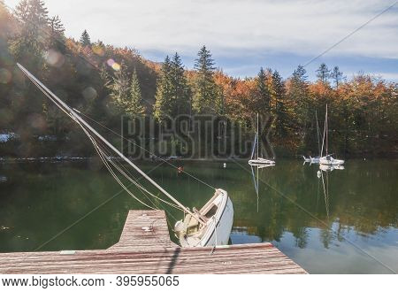 Capsized Sailboat Near The Pier On Lake Bohinj. Autumn Landscape In Slovenia