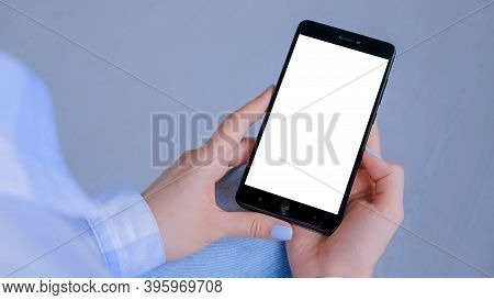Mockup Image: Woman Looking At Black Smartphone With White Blank Screen. Close Up View Of Woman Hand