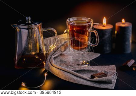 Transparent Glass Teapots With Tea On The Glass Stand With A Candle. Object. Dark Background, Herbs 