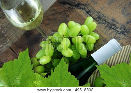 Hvidvin i glas, druer og vin flaske på Vintage træ