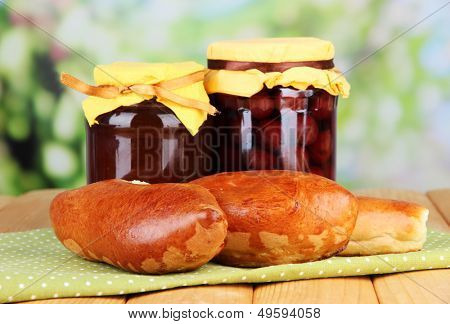 Empanadillas al horno frescos con mermelada de frutas, en la mesa de madera, sobre fondo brillante