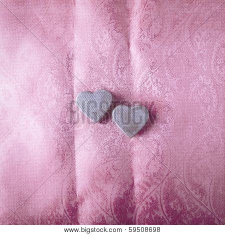 Two chocolate hearts on satin background in old style