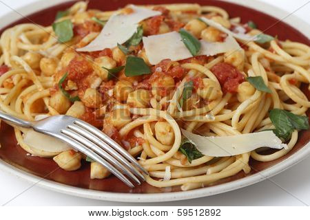 Spaghetti with a chickpea, tomato and chilli flakes sauce, garnished with fresh torn basil leaves and flakes of parmesan. This is a traditional Italian dish called spaghetti alla ceci