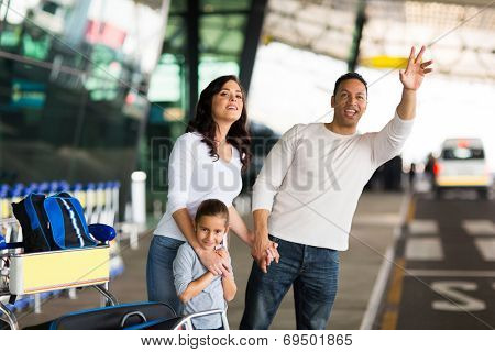 handsome man and his family hailing taxi at airport