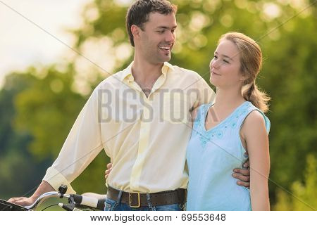 Two Young People Walking In The Park Together Embraced And Smiling.