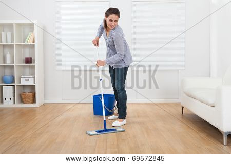 Woman Cleaning Hardwood Floor Of Living Room