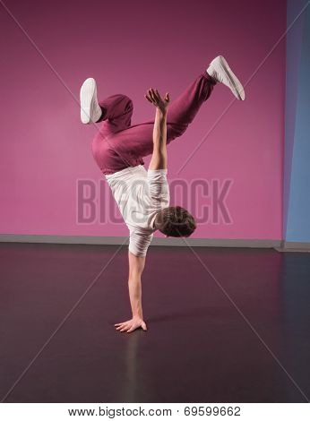 Cool break dancer doing handstand on one hand in the dance studio