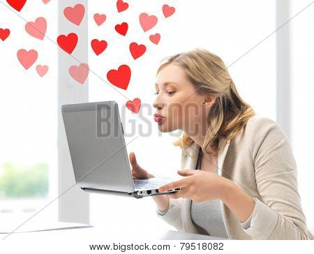 virtual relationships, online dating and social networking concept - woman sending kisses with laptop computer